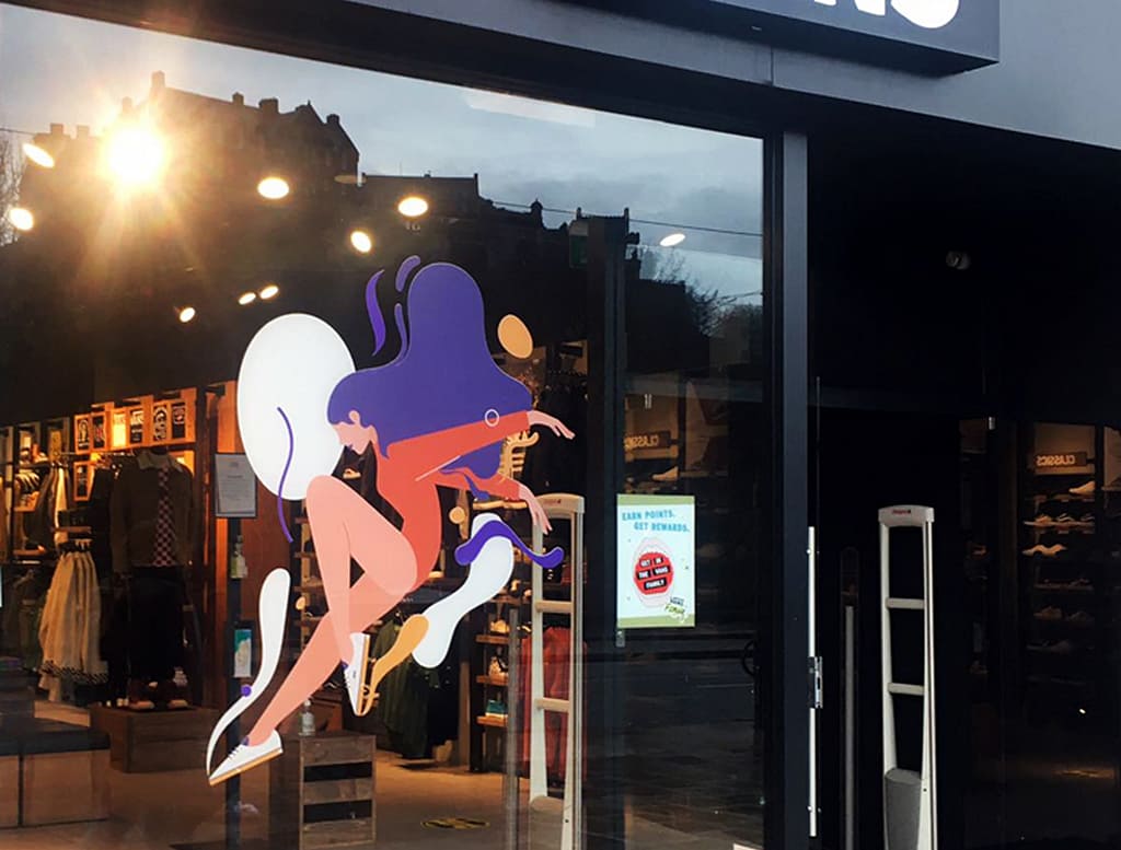 Store window of Vans Edinburgh featuring an illustration of a woman mid-jump with vibrant yellow and white blobs, promoting the "Make It Special" campaign.